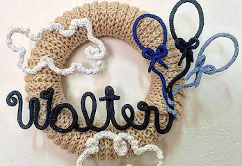 Ghirlanda intrecciata con scritta decorativa in filo blu, cuori e motivi chiari