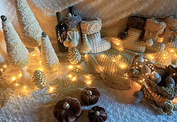 Composizione decorativa invernale con alberelli chiari, pigne e luci calde